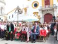 Celebración en el Parque de la Victoria, Sevilla. Personas vestidas con trajes tradicionales y sombreros, junto a un edificio histórico.
