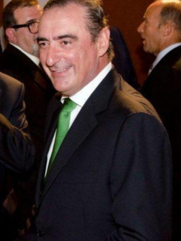 Un hombre con una camisa blanca y corbata verde, posando en un evento formal.