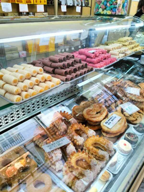 Un mostrador de pastelería con una variedad de dulces y galletas, incluyendo rosquillas, pastelitos de chocolate, rosquillas y pasteles.