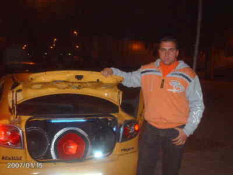 Persona posando junto a un Renault Megane con el portón abierto, noche urbana.