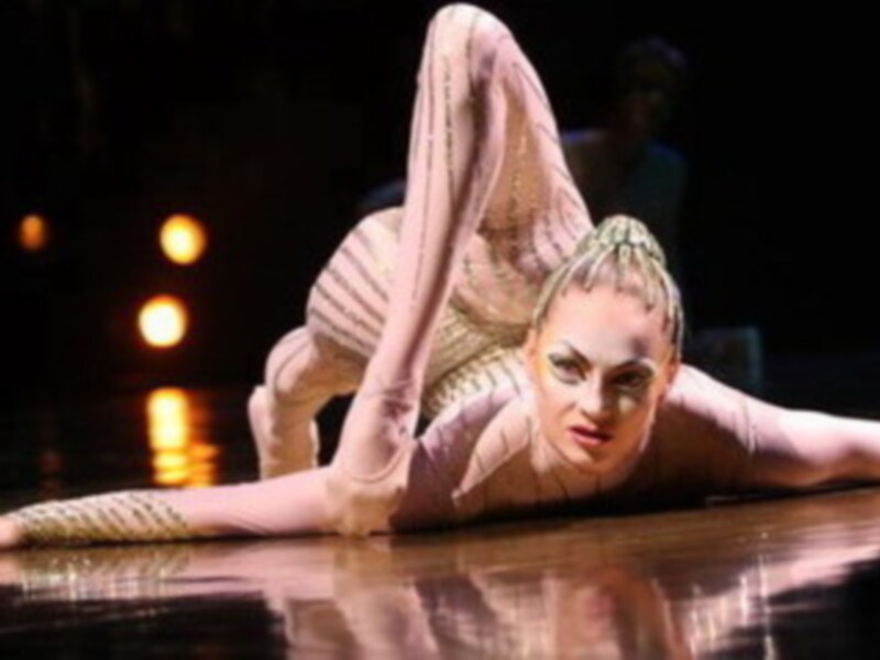 Una bailarina en un tutú rosa y blanco, realizando una pose acrobática sobre el suelo.