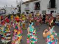 Desfile de carnaval en una localidad española, con participantes vestidos con trajes coloridos y floreados.