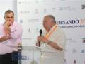 Dos personas hablando en un evento deportivo en San Fernando 2010, con logos de patrocinio y el lema "Andalucía, Ruta Española por el Deporte".