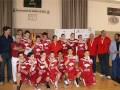 Equipo de baloncesto celebrando un triunfo, con medallas y camisetas rojas.