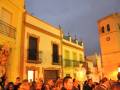 Una procesión religiosa en una ciudad española, con iglesias y gente reunida al atardecer.