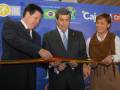 Inauguración de una instalación, con una persona cortando una cinta en la que se puede ver la bandera de Brasil y la palabra 'Cajamar'.