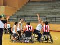 Jugadores de baloncesto en silla de ruedas en un juego en una cancha deportiva.