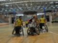 Jugadores de baloncesto en silla de ruedas en acción durante un partido en una cancha deportiva.