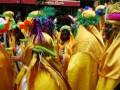 Desfile de carnaval con participantes vestidos de amarillo y adornos coloridos en una calle animada.