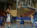 Jugadoras en acción durante un partido de baloncesto, con una jugadora lanzando el balón hacia la canasta.