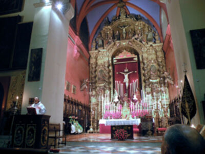 Interior de una iglesia con un altar elaborado y un crucifijo en el centro.