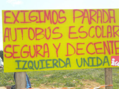 Cartel amarillo con texto en rojo y verde pidiendo parada segura para autobús escolar.