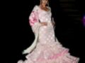 Elegante vestido de flamenca con lunares blancos y detalles en rosa, complementado con un tocado floral.