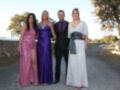 Cuatro jóvenes posan en un camino rural, vestidos con elegantes vestidos de noche: una en lila, otra en morado, un hombre en negro y otra en gris.
