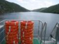 Vista desde el barco de dos anillas de salvamento en el lago, con montañas en el fondo y un cielo azul con algunas nubes.