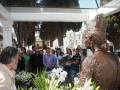 Celebración en un cementerio con una estatua de bronce y personas en la ceremonia.
