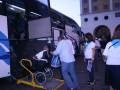 Un hombre en silla de ruedas es ayudado a subir un ascensor para personas con discapacidades en el frente de un autobús grande. La imagen muestra una escena de transporte público accesible, con varios pasajeros esperando en la fila.