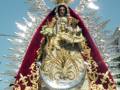 Imagen de una Virgen María con un manto rojo y dorado, rodeada por una corona de estrellas.