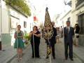 Personas con un león de mar en la bandera en una calle con edificios blancos y balcones con plantas enmarcados.