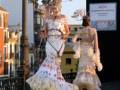 Desfile de trajes de flamenca con vestidos florales y adornos en Sevilla.