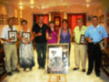 Grupo de personas celebrando el XII Festival del Mojácarite, posando con sus premios y un póster que muestra a una persona en el centro.