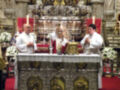 Imagen de un altar en una iglesia con sacerdotes celebrando. La imagen muestra detalles religiosos y decoración de la iglesia, con sacerdotes en trajes blancos celebrando una ceremonia religiosa.