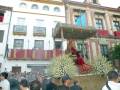 Festividad religiosa en un edificio histórico con banderas y flores.