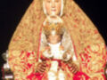 Estatua religiosa de la Virgen María con vestimenta dorada y roja, sosteniendo a un niño.