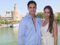 Dos personas posan frente a un río con el Torre del Oro de Sevilla al fondo.
