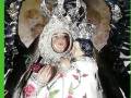 Imagen religiosa de una Virgen con corona y vestido bordado, rodeada por un marco dorado.