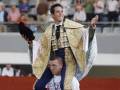 Un torero en traje de capea, sonriendo y saludando a la audiencia en una corrida de toros.