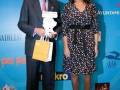 Premios Solidarios en Madrid, con un hombre y una mujer posando frente a un fondo azul con logos de patrocinadores.
