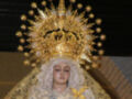 Virgen con corona dorada y estrellas, rodeada de velas.