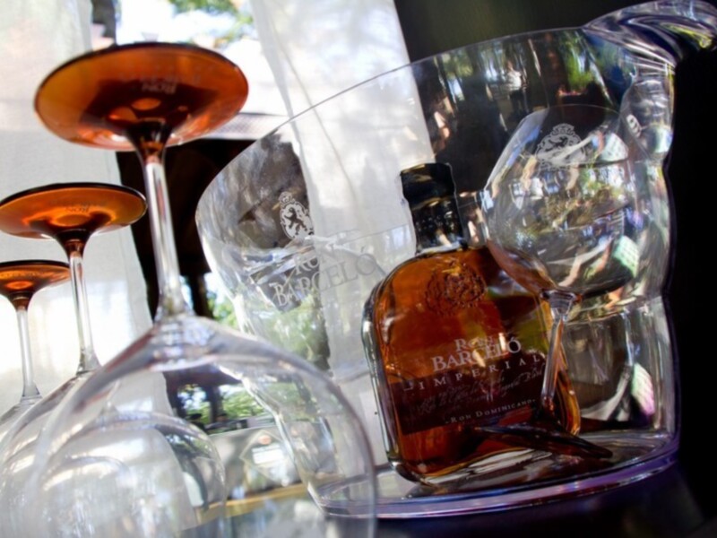 Una botella de whisky Royal Salute junto a copas de cristal vacías, iluminadas por la luz natural.
