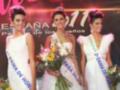 Tres mujeres posando en un escenario con coronas y sashes, probablemente en una competencia de belleza.