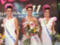 Concurso de belleza 'Dama de Honor 2011' con tres candidatas en vestidos blancos y coronas de flores, sosteniendo ramas de flores.