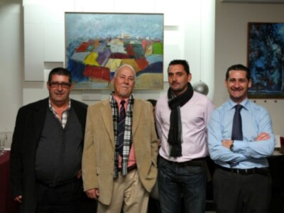 Tres hombres posan frente a una pintura abstracta en un entorno formal.