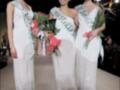 Tres mujeres vestidas con elegantes vestidos blancos y coronas posan juntas en un escenario, cada una con un título de belleza.