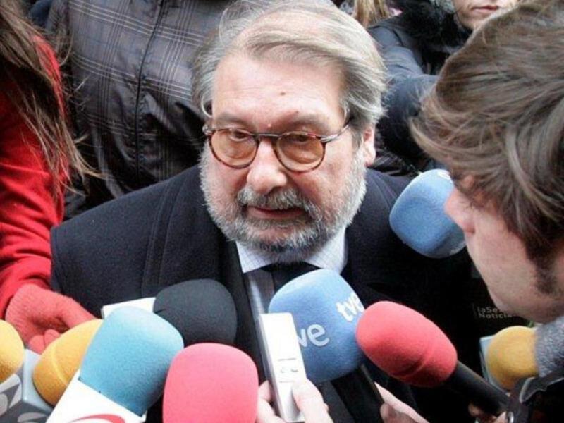 El hombre está rodeado de micrófonos, hablando a la prensa.
