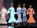 Una escena de desfile de moda flamenca con cuatro modelos en trajes tradicionales.
