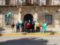 Un grupo de personas con banderas y gorros en una calle frente a un edificio histórico.