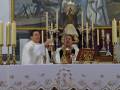Celebración religiosa en un altar con dos sacerdotes y una imagen de la Virgen María en el fondo.