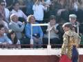 Torero in traditional attire performing in a bullfight, with a crowd of spectators in the background.