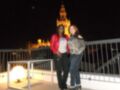 Dos personas posan en un balcón de noche con la Giralda de Sevilla al fondo.