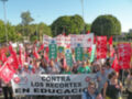 Un grupo de personas con pancartas y banderas rojas protestan contra los recortes en educación.