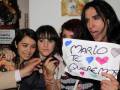 Cuatro personas posan juntas, una sosteniendo un cartel que dice 'MARIO TE TE QUIERE'.