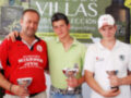 Tres personas posan con trofeos en un evento deportivo, con una pancarta de 'Villas' en el fondo.