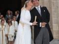 Una boda real en un palacio con una novia vestida de blanco y un novio besándose.