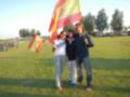 Tres personas celebrando con banderas españolas en un parque soleado.