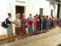 Grupo de mujeres esperando en fila frente a una fachada de edificio blanco.